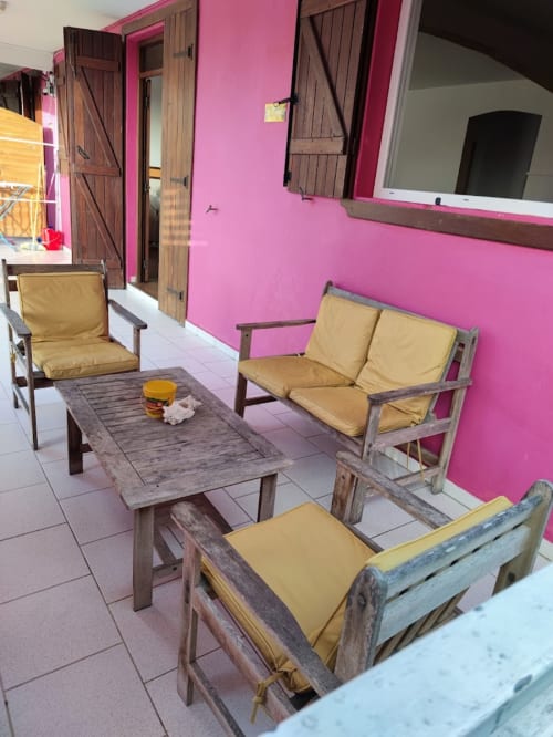 Espace de détente rose vif à la Résidence Les 2 Moulins au Moule avec mobilier en bois et coussins jaunes
