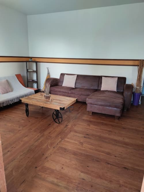 Séjour moderne à la Résidence Les 2 Moulins avec canapé d'angle bordeaux, table basse en bois et parquets à Le