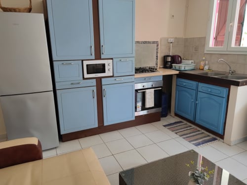 Cuisine avec armoires bleues, cuisinière, micro-ondes et évier à la Résidence Les 2 Moulins au Moule, Guadeloupe