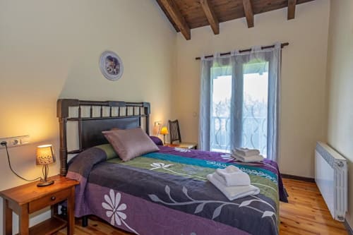 Acogedora habitación en la villa Torre Gelbert de Puigcerdà con vigas de madera, ropa de cama colorida, balcón con vistas a montaña y ambiente cálido