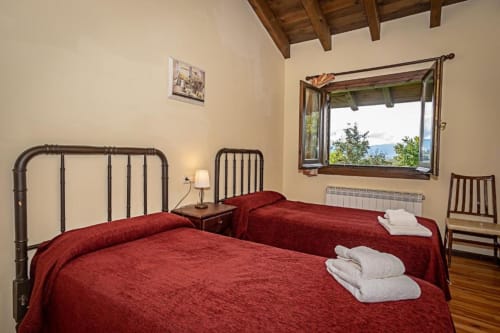 Dormitorio de la villa Torre Gelbert en Puigcerdà con camas gemelas, vistas a la montaña y vigas de madera rústica