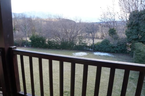 Barandilla de balcón con vistas al jardín nevado y árboles desnudos de invierno en la villa Torre Gelbert de Puigcerdà