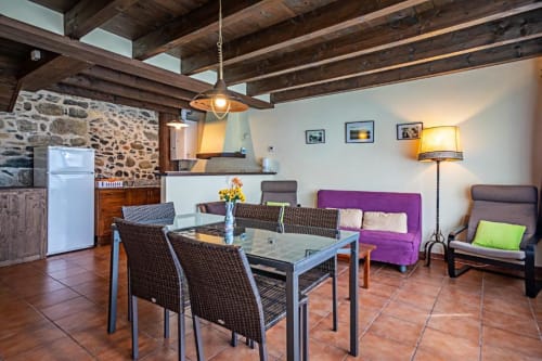 Interior moderno de villa en Torre Gelbert, Puigcerdà con vigas vistas, comedor, sofá morado y muros de piedra