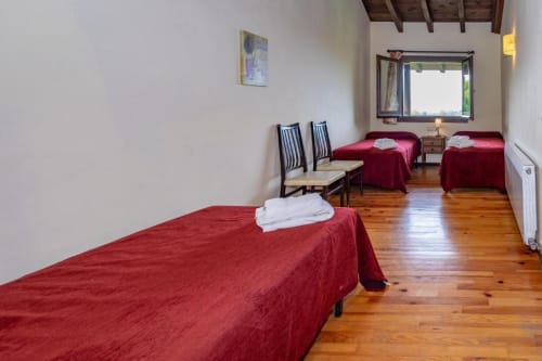 Espacioso dormitorio de villa en Torre Gelbert con camas rojas, pisos de madera y vistas a las montañas en Puigcerdà