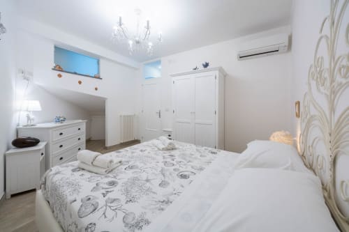 Luminosa camera da letto con vista mare a Villa Costanza, Maiori. Arredamento bianco, biancheria floreale, comfort moderni incluso climatizzatore