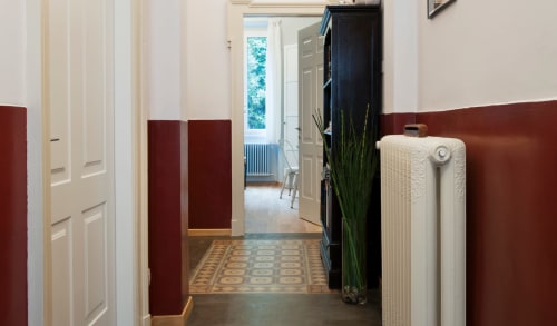 Elegante corridoio del Porta Tosa B&B a Milano con rivestimenti bordò, porte bianche e piastrelle geometriche