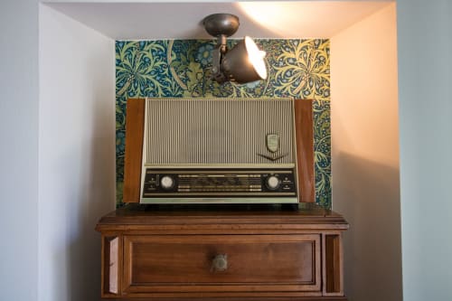 Radio vintage su comò in legno con carta da parati turchese decorata presso il bed and breakfast Porta Tosa Milano