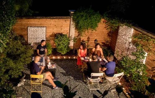 Gli ospiti si riuniscono nell'intima corte di Porta Tosa a Milano di notte, illuminata da luci decorative e verdure