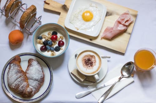 Colazione Porta Tosa Milano con cornetti, uova, bacon, yogurt, caffè e succo di frutta