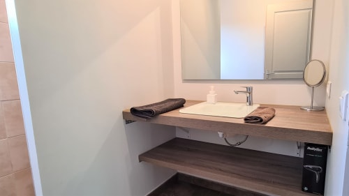 Modern bathroom vanity with wooden countertop, vessel sink, and mirror at Villas Lantana villa in Lecci