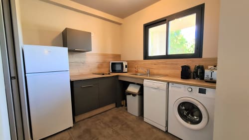 Modern studio kitchen at Villas Lantana in Lecci with white fridge, washing machine, microwave, and wooden countertops