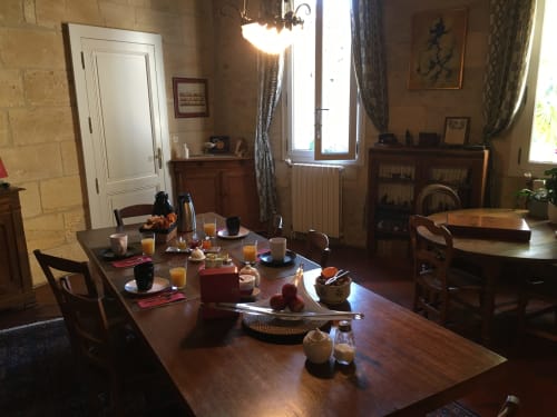 Salle à manger élégante du Sous Les Marronniers avec table en bois dressée pour le petit-déjeuner, mobilier d'époque et murs en pierre