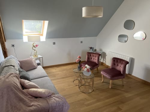 Wohnbereich des Studios im Château Ségot mit Samtsesseln in Burgunderrot, grauem Sofa, Oberlicht und Holzboden in Neuilly-le-Réal