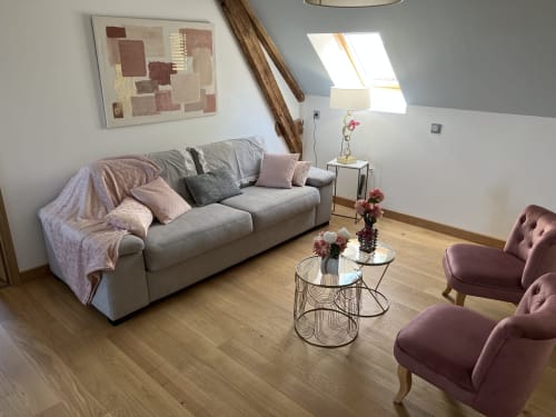 Moderner Wohnbereich im Château Ségot mit grauem Sofa, burgunderfarbenen Sesseln, Glascouchtischen und Dachfenster