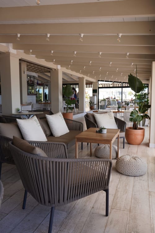Modern outdoor lounge area at Hotel Sa Roqueta in Can Picafort with woven chairs, wooden tables, and tropical plants