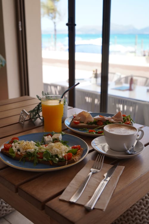 Beachfront breakfast at Hotel Sa Roqueta with fresh salad, coffee, and ocean view in Can Picafort