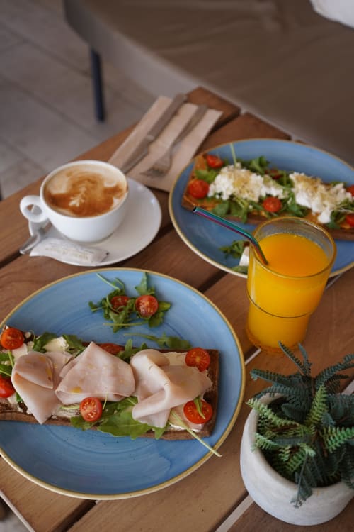 Colazione all'Hotel Sa Roqueta: bruschetta al prosciutto, insalate fresche, succo d'arancia e cappuccino su tavolo di legno a Can