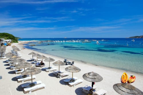 Spiaggia di Villas Lantana a Lecci con ombrelloni, lettini, acqua turchese e barche ormeggiate