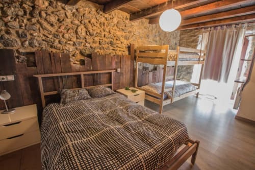 Espaciosa habitación en La Calma De Bellver con cama doble, litera, vigas de madera, muros de piedra y comodidades modernas