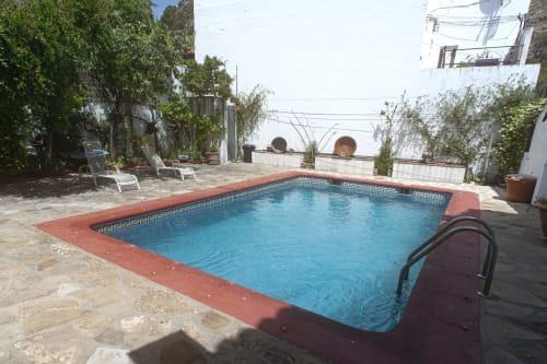 Swimming pool with red terracotta edge at La Casa De La Abuela Regina in Grazalema, surrounded by lounge chairs and white