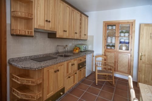 Cocina totalmente equipada en el Apartamento Simancón de La Casa De La Abuela Regina, Grazalema con muebles de madera y granito