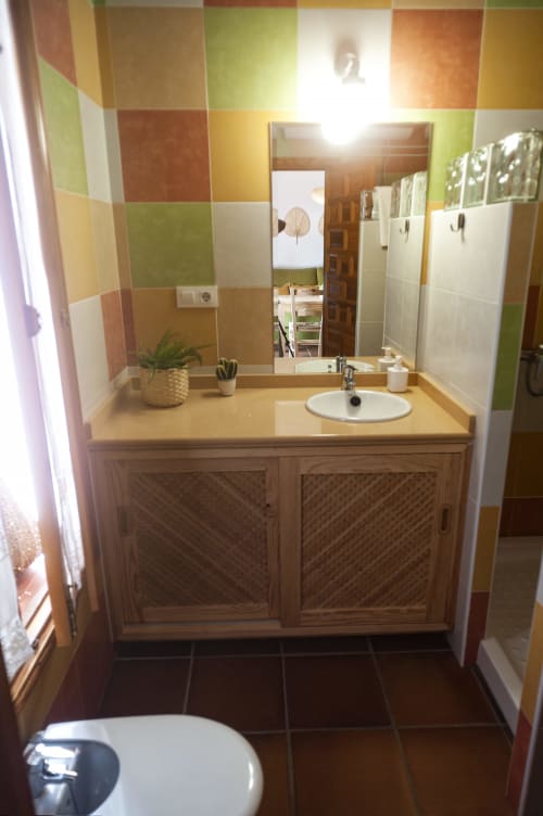 Baño colorido en Apartamento Simancón de La Casa De La Abuela Regina, Grazalema, con mueble de madera y azulejos decorativos