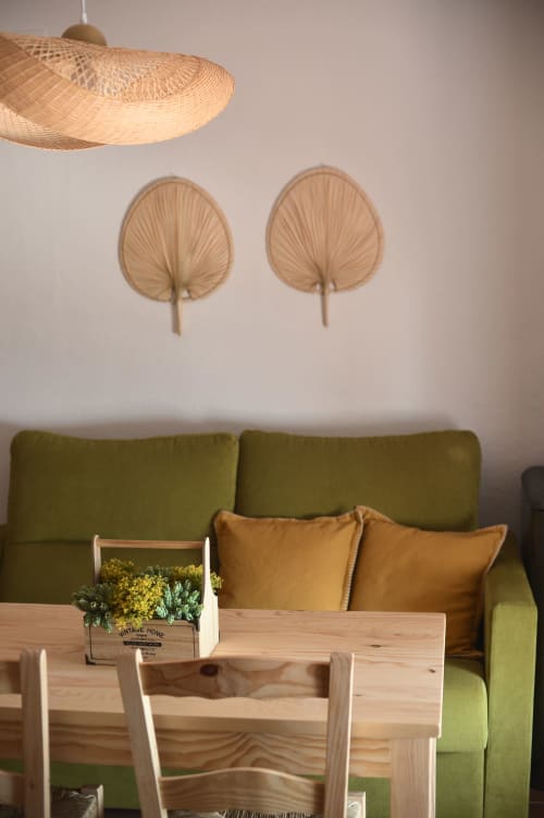 Interior del apartamento de Grazalema con sofá verde, mesa de madera, lámpara colgante natural y decoración tejida en pared