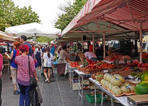 Vivace mercato agricolo a Lecci, Francia con esposizioni colorate di prodotti freschi, bancarelle di venditori e clienti che sfogliano frutta