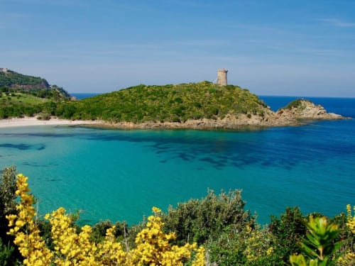 Acque turchesi e piccola caletta sabbiosa con torre storica nelle Villas Lantana a Lecci, Corsica
