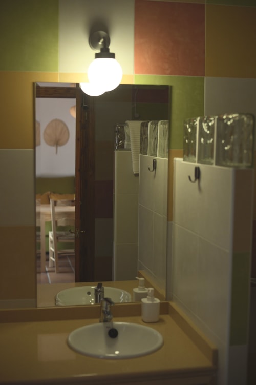 Lavabo y espejo del baño con apliques de pared en el Apartamento Simancón de La Casa De La Abuela Regina, Grazalema