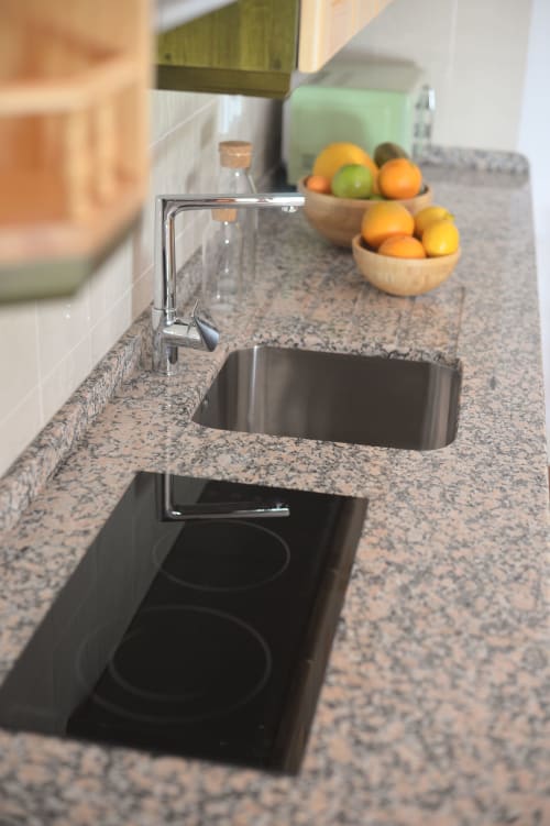Moderna cocina con fregadero de acero cromado, encimera de granito y frutas cítricas frescas en cuencos de madera en Apartamento Simancón