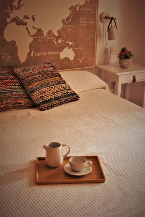 Dormitorio en La Casa De La Abuela Regina en Grazalema con mapa mundi, almohadas coloridas y bandeja de madera con té