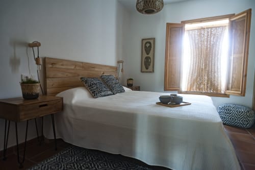 Bright bedroom with wooden bed, patterned pillows, nightstand, and glazed doors opening to balcony at La Casa De La Abuela