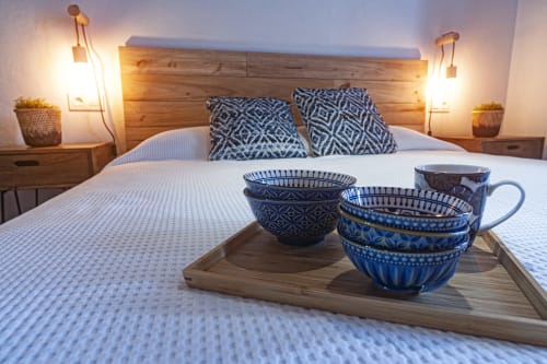 Cozy bedroom at La Casa De La Abuela Regina in Grazalema with wooden headboard, blue patterned pillows, and decorative