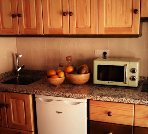 Kitchen counter in Pinsapar apartment at La Casa De La Abuela Regina with wooden cabinets, granite countertop, microwave, and