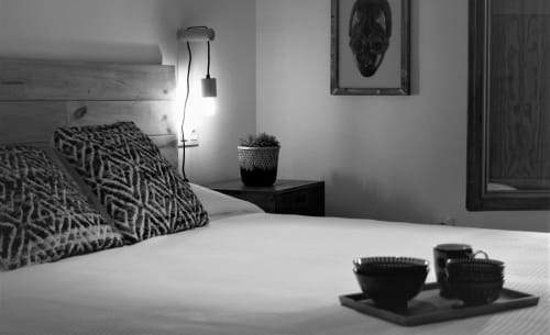 Modern bedroom at La Casa De La Abuela Regina in Grazalema with white bedding, patterned pillows, bedside lamp, potted plant,
