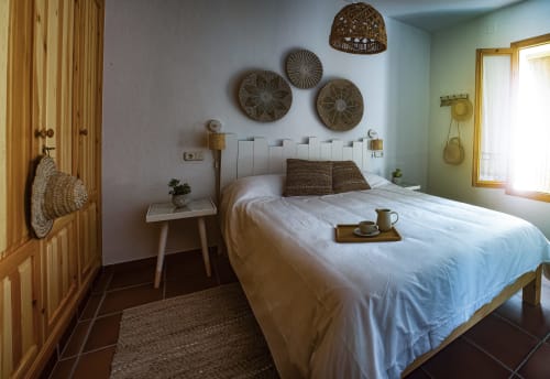 Acogedora habitación del Apartamento Gaduares en La Casa De La Abuela Regina, Grazalema, con cama blanca, decoración tejida y luz natural