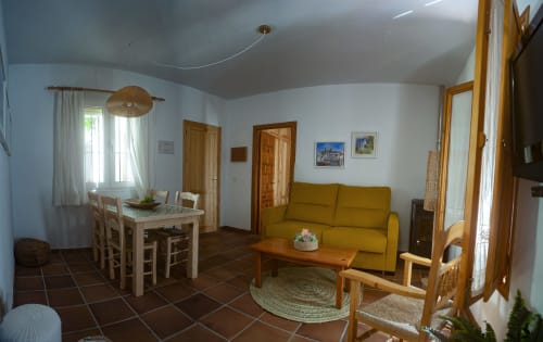 Sala de estar del apartamento Gaduares en La Casa De La Abuela Regina en Grazalema, Cádiz con sofá amarillo, mesa de comedor y