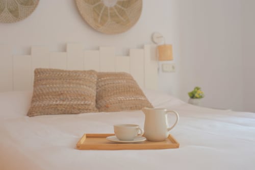 Habitación en La Casa De La Abuela Regina en Grazalema con servicio de café en bandeja de madera, almohadas tejidas y decoración minimalista