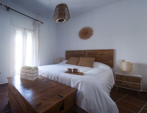 Bright bedroom in Zurraque Apartment at La Casa De La Abuela Regina, Grazalema, with wooden bed, white linens, and woven