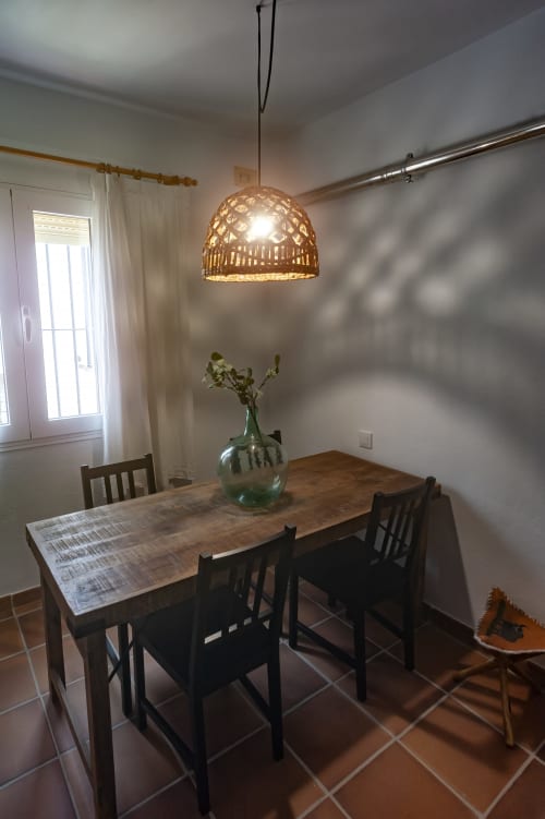 Dining area in Zurraque Apartment at La Casa De La Abuela Regina, Grazalema with wooden table, woven pendant light, and green