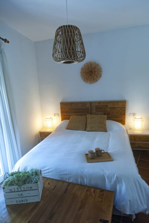 Cozy bedroom in Zurraque Apartment, Grazalema, with woven pendant light and wooden furnishings