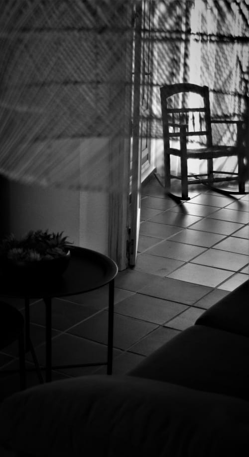 Sunlit apartment interior at La Casa De La Abuela Regina in Grazalema with wooden chair, tiled floor, and window shadows