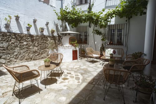 Charming courtyard at La Casa De La Abuela Regina in Grazalema with wicker chairs, stone walls, and hanging plants