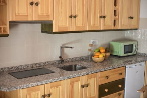 Cocina moderna con gabinetes de madera, encimeras de granito y backsplash de azulejos blancos en La Casa De La Abuela Regina