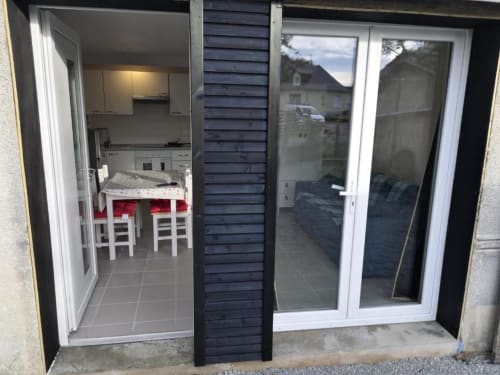 Entrée de l'appartement Sci Saviya à Égletons avec cuisine, salle à manger et vue sur le jardin par les portes vitrées