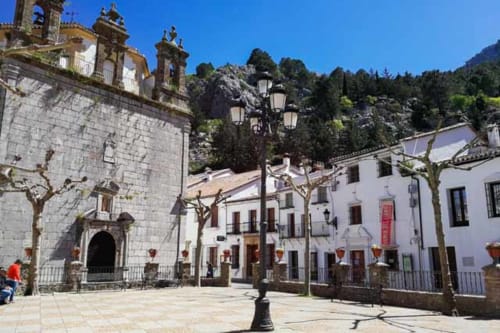 Historic plaza in Grazalema with white buildings, stone church, and mountain backdrop near La Casa De La Abuela Regina hotel