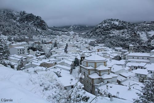 Snow-covered village of Grazalema nestled between mountains, featuring white buildings and traditional architecture