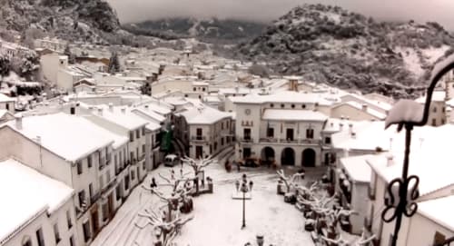 Snow-covered Plaza Mayor in Grazalema with whitewashed buildings and surrounding mountains at La Casa De La Abuela Regina