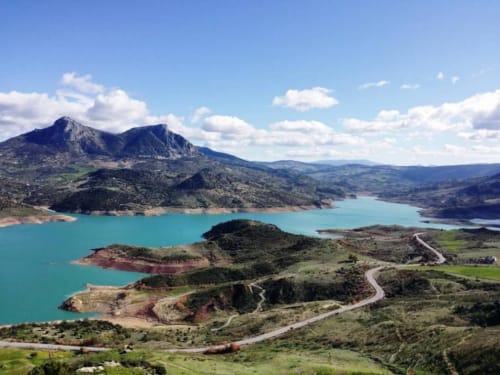 Turquoise lake surrounded by green hills and mountain peaks near Grazalema, Cádiz, Spain